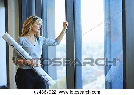 Stock Image - "Portrait of mature female architect with plans in skyscraper office, Brussels, Belgium". Fotosearch
