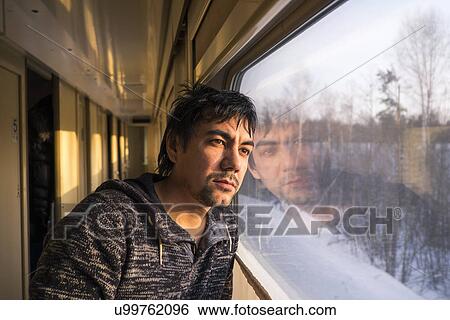 Stock Photograph - Portrait of mid adult man gazing out of train window. Fotosearch