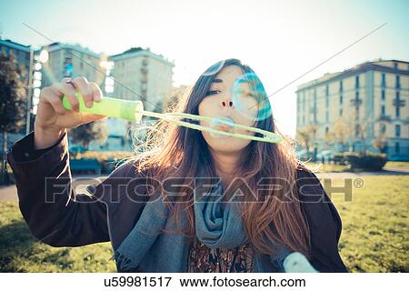 Portrait of mid adult woman blowing bubbles in park View Large Photo Image Stock Photo - Portrait of mid adult woman blowing bubbles in park. Fotosearch