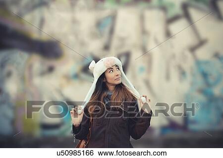 Portrait of mid adult woman wearing fur hat in front of graffiti wall View Large Photo Image Stock Photograph - Portrait of mid adult woman wearing fur hat in front of graffiti wall. Fotosearch