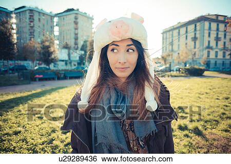 Stock Photograph - Portrait of mid adult woman wearing pig fur hat in park. Fotosearch