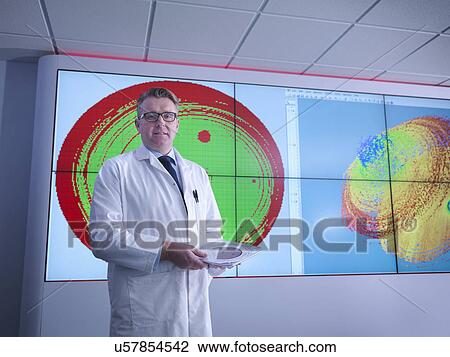 Stock Image - Portrait of scientist in front of graphical display of silicon wafer on screens. Fotosearch