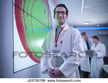 Stock Photo - Portrait of scientist in front of graphical display of silicon wafer on screens. Fotosearch