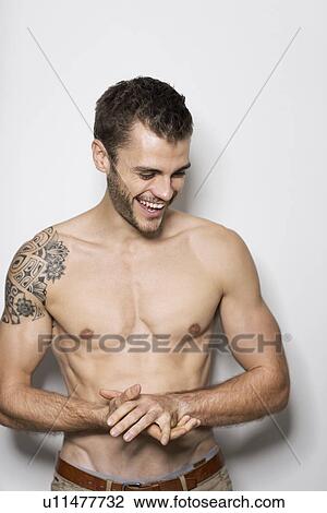 Portrait of smiling bare chested young man with tattoo on shoulder View Large Photo Image Stock Image - Portrait of smiling bare chested young man with tattoo on shoulder. Fotosearch