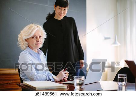 Portrait of two mature businesswomen at boardroom table View Large Photo Image Stock Image - Portrait of two mature businesswomen at boardroom table. Fotosearch