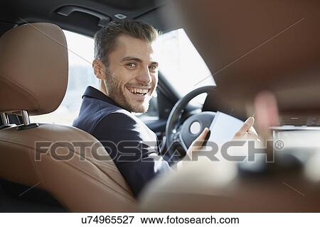 Portrait of young businessman using digital tablet in car View Large Photo Image Stock Photo - Portrait of young businessman using digital tablet in car. Fotosearch