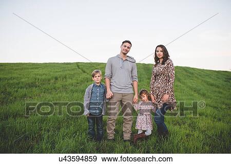 Portrait of young couple with son and daughter strolling in grassy field View Large Photo Image Stock Photo - Portrait of young couple with son and daughter strolling in grassy field. Fotosearch