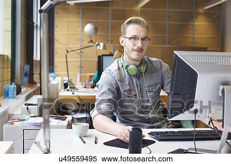 Portrait of young man using computer at office desk View Large Photo Image Stock Photography - Portrait of young man using computer at office desk. Fotosearch