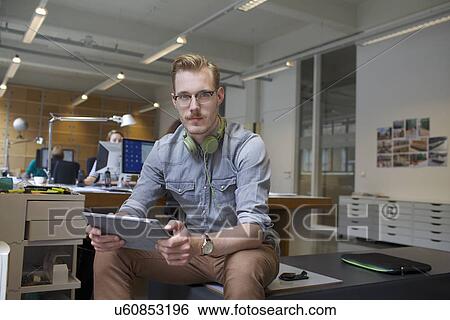 Portrait of young man using digital tablet in office View Large Photo Image Stock Photograph - Portrait of young man using digital tablet in office. Fotosearch