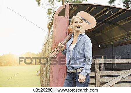 Stock Image - "Portrait of young woman, holding guitar on shoulder". Fotosearch
