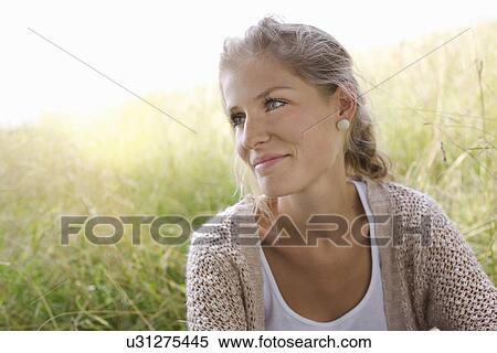 Stock Photography - Portrait of young woman in field. Fotosearch