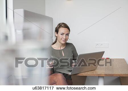 Stock Photo - Portrait of young woman using laptop in office. Fotosearch