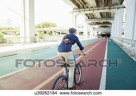 Picture - "Rear view of male tourist cycling in cycle lane, Seoul, South Korea". Fotosearch