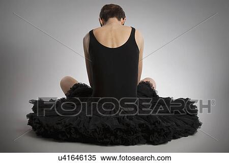 Stock Photography - Rear view of woman sitting on floor wearing black tutu. Fotosearch