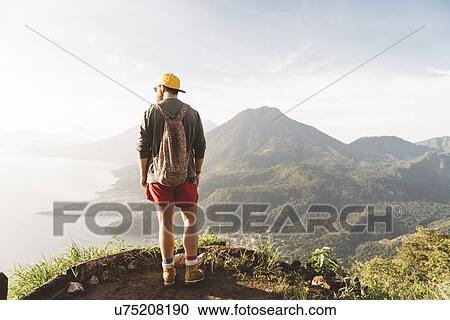 Stock Image - "Rear view of young man looking out over Lake Atitlan, Guatemala". Fotosearch