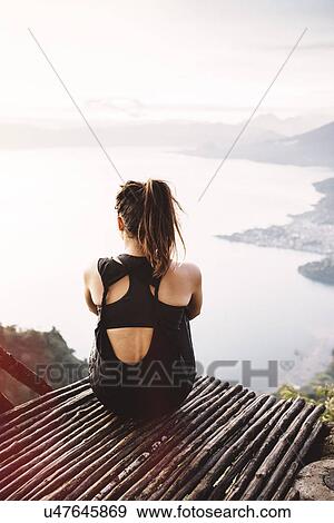 Stock Photo - "Rear view of young woman on balcony looking out over Lake Atitlan, Guatemala". Fotosearch