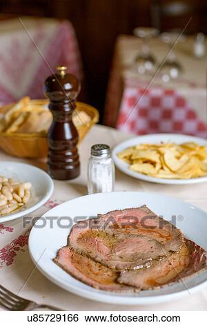 Stock Photograph - "Restaurant plate of roast beef with white beans and potato fries, Tuscany, Italy". Fotosearch