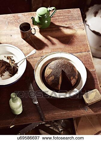 Stock Photo - Rustic table with dish of steamed treacle pudding and teapot. Fotosearch