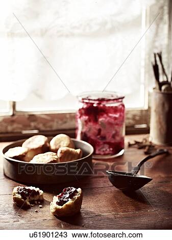 Stock Image - Rustic windowsill with rosella jam and puftaloons (fried scones). Fotosearch