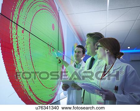 Stock Image - Scientists studying graphical display of silicon wafer on screens. Fotosearch