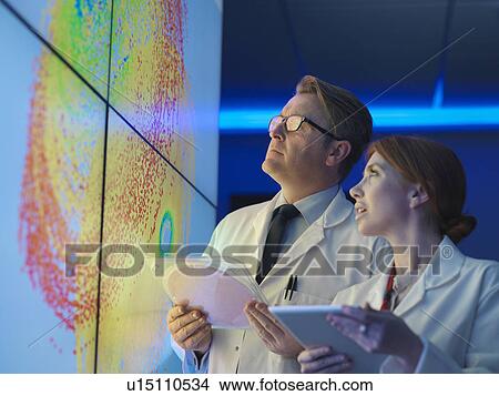 Scientists with silicon wafer studying graphical display of wafer on screens View Large Photo Image Picture - Scientists with silicon wafer studying graphical display of wafer on screens. Fotosearch