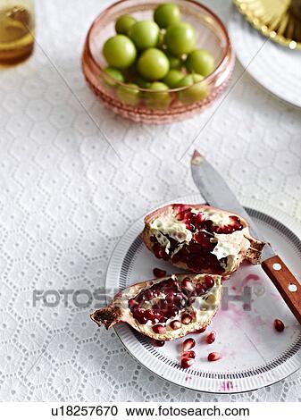 Stock Image - Still life with pomegranate and a bowl of green olives. Fotosearch