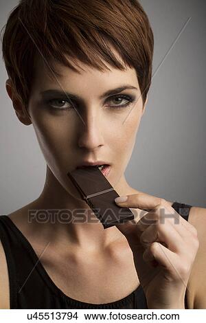 Studio portrait of woman eating dark chocolate View Large Photo Image Picture - Studio portrait of woman eating dark chocolate. Fotosearch
