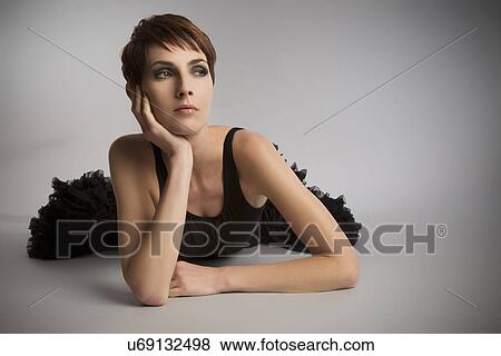 Stock Photo - Studio portrait of woman lying on floor wearing black tutu. Fotosearch