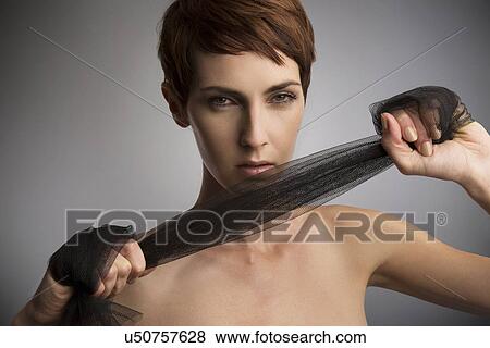 Stock Photo - Studio portrait of woman pulling black silk scarf around hands. Fotosearch
