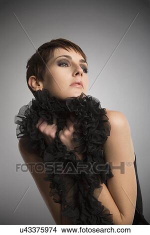 Studio portrait of woman wearing and holding onto black boa ruffle View Large Photo Image Picture - Studio portrait of woman wearing and holding onto black boa ruffle. Fotosearch