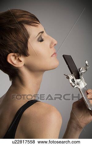 Studio portrait of woman with eyes closed holding up dark chocolate bar View Large Photo Image Stock Photo - Studio portrait of woman with eyes closed holding up dark chocolate bar. Fotosearch