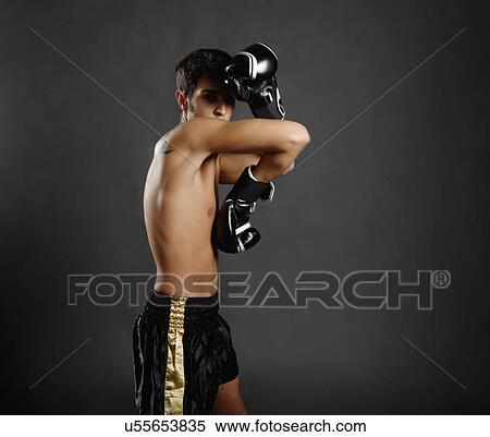 Stock Photography - Studio portrait of young man with boxing gloves poised defensively. Fotosearch