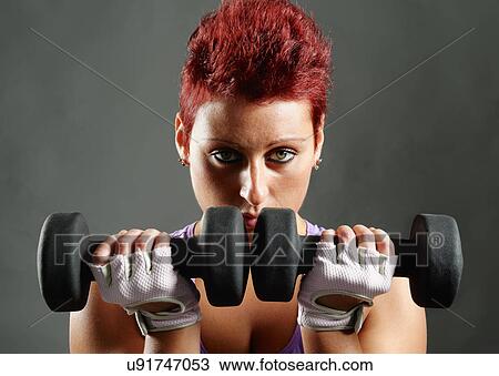 Studio portrait of young woman poised with dumbbells in front of face View Large Photo Image Stock Image - Studio portrait of young woman poised with dumbbells in front of face. Fotosearch