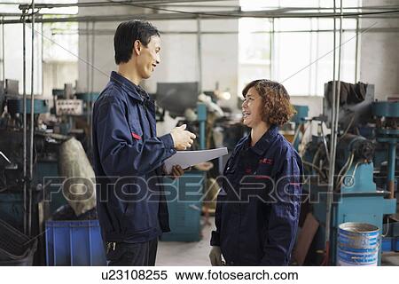 Stock Photography - "Supervisor explaining to worker in crane factory, Jiangsu Province, China". Fotosearch