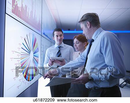 Three business people discuss graphs on screen in meeting room View Large Photo Image Stock Photo - Three business people discuss graphs on screen in meeting room. Fotosearch