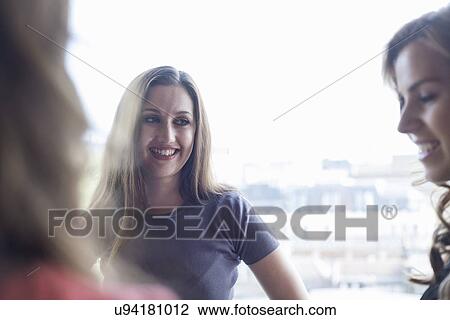 Three businesswomen having informal meeting in front of office window View Large Photo Image Stock Image - Three businesswomen having informal meeting in front of office window. Fotosearch