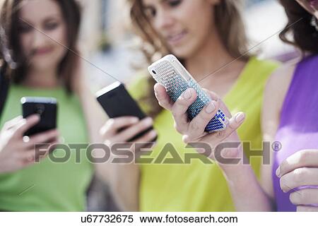 Three businesswomen using mobile phones outside office View Large Photo Image Stock Photography - Three businesswomen using mobile phones outside office. Fotosearch
