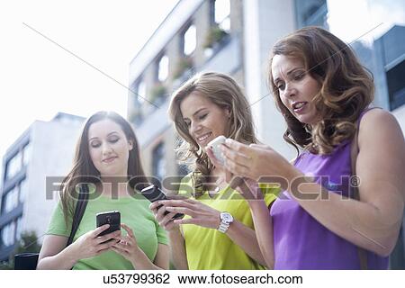 "Three businesswomen using mobile phones outside office, low angle view" View Large Photo Image Stock Image - "Three businesswomen using mobile phones outside office, low angle view". Fotosearch