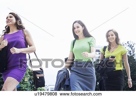 "Three businesswomen walking together, outdoors, low angle view" View Large Photo Image Stock Photo - "Three businesswomen walking together, outdoors, low angle view". Fotosearch