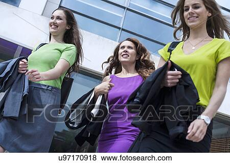 Stock Photo - "Three businesswomen walking together, outdoors, low angle view". Fotosearch