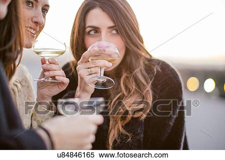 Stock Photography - "Three female friends drinking together at party, close-up". Fotosearch