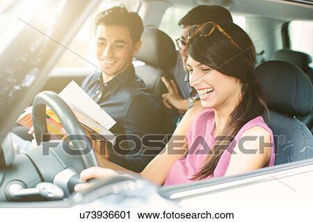 Three young adult friends in car looking at travel guide View Large Photo Image Stock Image - Three young adult friends in car looking at travel guide. Fotosearch