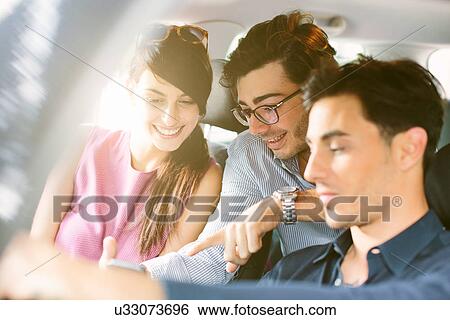 Three young adult friends in car navigating with smartphone View Large Photo Image Stock Photograph - Three young adult friends in car navigating with smartphone. Fotosearch