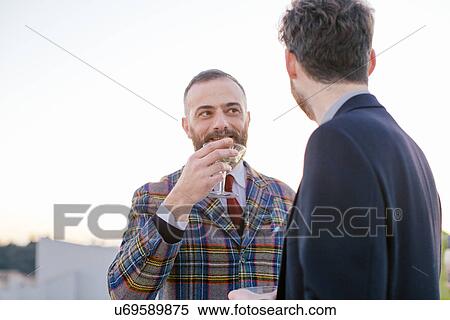 Stock Photography - Two friends drinking together at party. Fotosearch