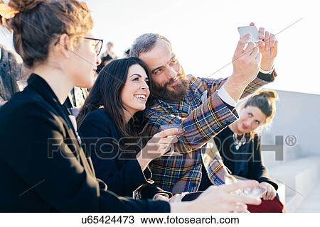 "Two friends taking self portrait at party, using smartphone" View Large Photo Image Stock Image - "Two friends taking self portrait at party, using smartphone". Fotosearch