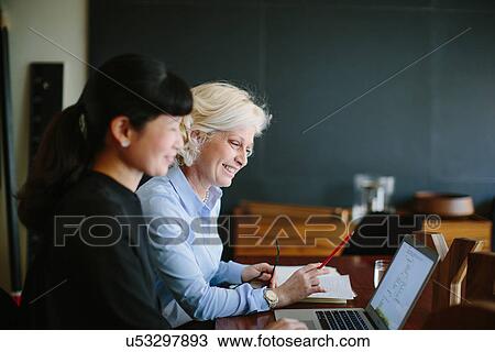 Stock Image - Two mature businesswomen having informal office meeting. Fotosearch