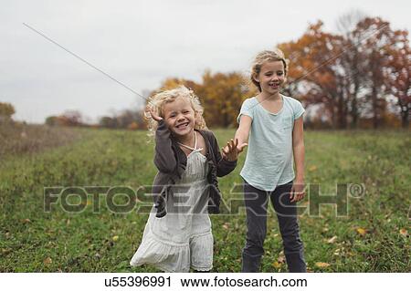 Stock Image - Two sisters playing together in field. Fotosearch
