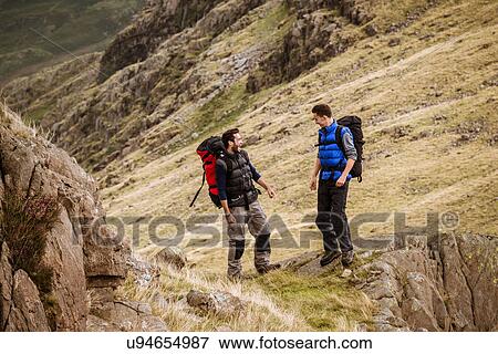 "Two young male hiking friends laughing and chatting, The Lake District, Cumbria, UK" View Large Photo Image Stock Photo - "Two young male hiking friends laughing and chatting, The Lake District, Cumbria, UK". Fotosearch