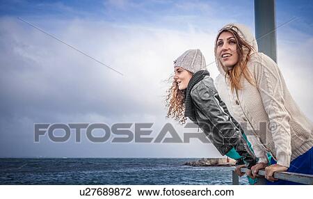 Two young women friends looking at sea from pier View Large Photo Image Stock Image - Two young women friends looking at sea from pier. Fotosearch