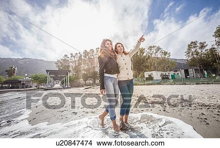 Two young women friends strolling barefoot on beach View Large Photo Image Picture - Two young women friends strolling barefoot on beach. Fotosearch